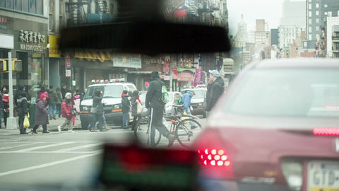 taxi cab stopped at busy intersection in Chinatown with people crossing street - meter and rearview mirror