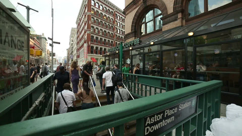people exiting Astor Place subway station stairs with Starbucks Coffee House in Cooper Square on summer day in Manhattan NYC