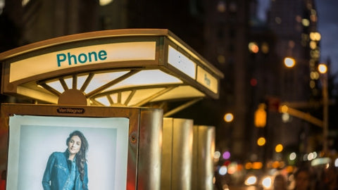public pay phone with ad of beautiful model at night in Manhattan