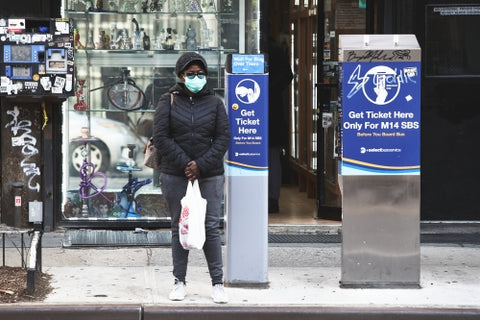 woman in mask during covid pandemic with shopping bag on sidewalk NYC