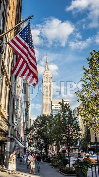 Empire State Building and American flag - summer day in Manhattan - street view of tall landmark skyscraper