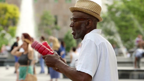 old man playing shakers and singing in Washington Square Park - elderly musician performing in summer in NYC