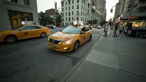 taxi cab double parked and kid skateboarding on East 8th street in Manhattan NYC