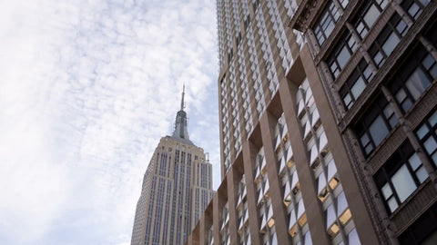 Empire State Building towering over Manhattan skyscrapers - upward view from moving car