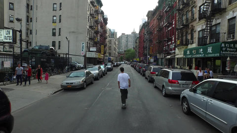 kid skating past cars in Chinatown - ascending above rooftops in New York City NYC