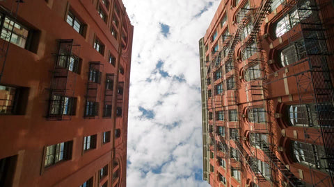 tilting down from SoHo buildings to quiet cobblestone street with cars parked on either side in NYC