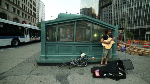 musician playing guitar in Cooper Square on summer day in Manhattan NYC