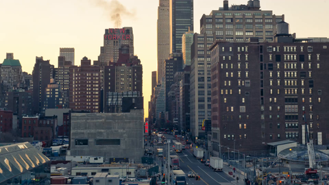 slow zoom out from Empire State Building and construction site with crane at sunset in Midtown Manhattan - 4K timelapse with cars driving in NYC