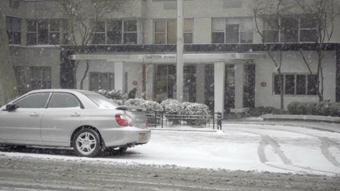 taxi cab with Wicked ad driving past residential building snowing on winter day in Manhattan NYC