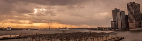 wide shot of East River at sunset with Statue of Liberty in distance - orange sky in early evening