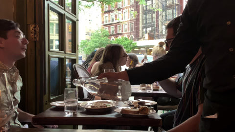 waiter pouring water - people having dinner interior restaurant in West Village New York City NYC