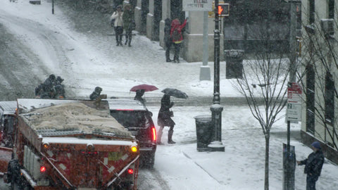 people walking with umbrellas in winter snowstorm in New York City