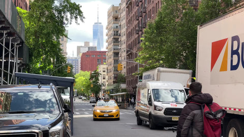taxi cab driving down street in Greenwich Village with Freedom Tower view man on bicycle Manhattan New York City NYC