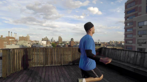 man jumping rope - athlete exercising with jump rope on roof top in with Manhattan skyline view on summer day in NYC
