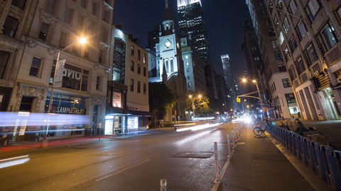 zooming out from Empire State Building lights at night with streaks of cars speeding below - 4K timelapse in Manhattan NYC