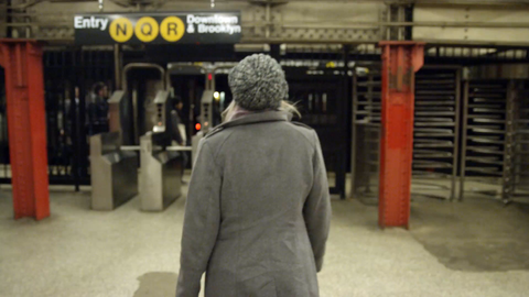 woman walking toward and entering subway turnstiles - swiping metro card in turnstile at N Q R train station - 4K slow motion in NYC