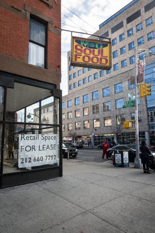 Harlem soul food restaurant with retail space for lease sign on corner - Uptown Manhattan during day