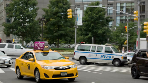 taxi cab driving by Columbus Circle on bright summer day in Manhattan NYC
