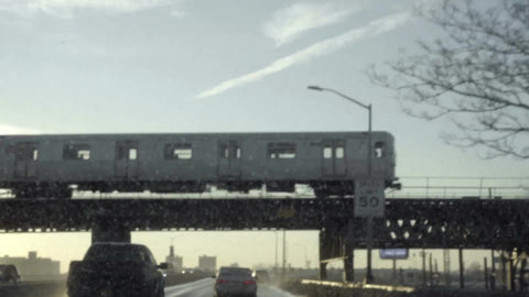 gritty subway train on elevated track riding at sunset in Brooklyn NYC