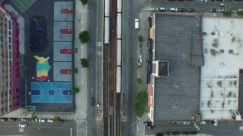 aerial over 1 train running into tunnel - uptown and downtown trains crossing paths on elevated track running through Harlem from overhead view