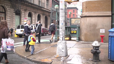 super slow motion of people walking on Broadway and Prince street by subway entrances in SoHo NYC on wet fall day