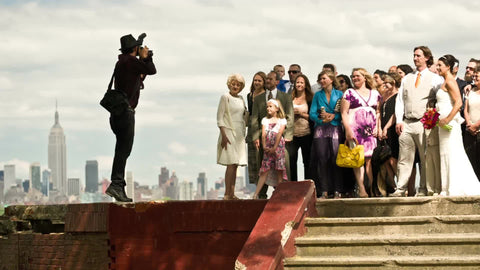 wedding photographer taking a picture with Empire State Building and Manhattan skyline in background on summer day in NYC