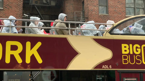 raining tourists with ponchos on rainy day on tourim red Big Bus New York City NYC