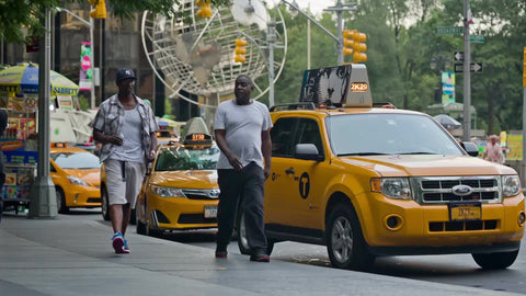 two men walking with Columbus Circle globe statue and taxicabs in background on summer day in Manhattan NYC