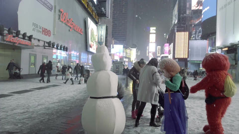 Elmo and Disney characters in costume taking photograph with tourist in Times Square winter blizzard - snowing at night