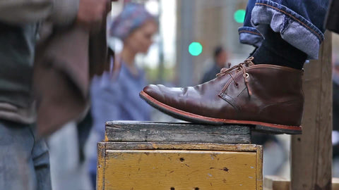 shoeshiner polishing man's boots on street - brown shoes getting polish in NYC