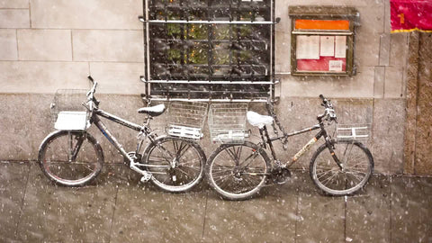 two bicycles outside in snow storm on street in NYC