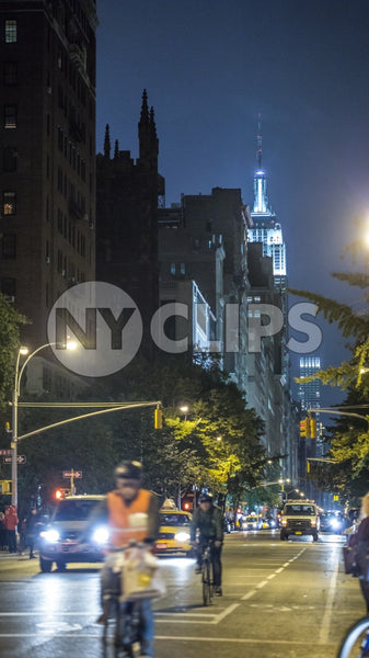 Empire State Building at night from Lower 5th Ave with bicycle delivery boy riding bike with helmet