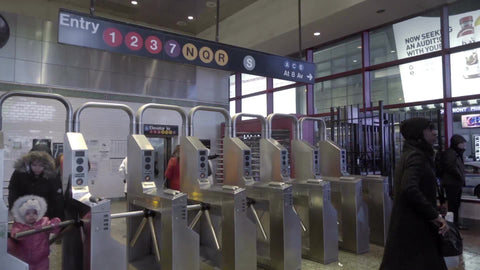 mother and her little girl exiting Times Square subway station turnstile in winter at night with sign