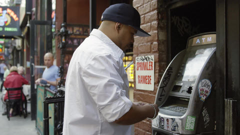 man swiping credit or debit card in ATM machine on Macdougal Street in Greenwich Village