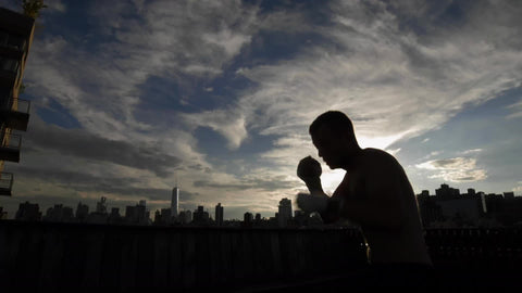 silhouette of man sparring on rooftop at sunset with Manhattan skyline in background in NYC