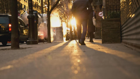 steaming grating with bright sun in early morning people walking in NYC