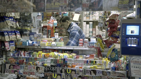newsstand man selling magazines and snacks on 42nd street off Times Square at night in New York City