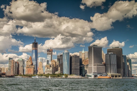 skyscrapers in Downtown Manhattan with Freedom Tower unfinished across East River on beautiful day