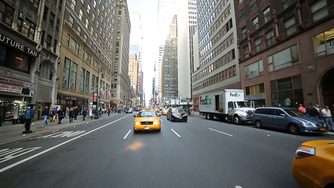 taxi cab driving on avenue in wide shot - passing crosswalk and intersection in Midtown Manhattan NYC