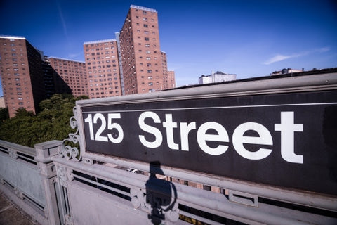 125th street subway sign in Harlem with housing projects in background in Uptown Manhattan NYC
