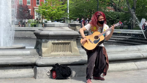 man with long dyed red hair playing acoustic guitar in Washington Square Park New York City NYC