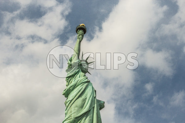 Statue of Liberty from side - medium shot - bright green over blue daytime sky with clouds