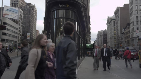 Flatiron Building on corner of 5th Ave with people walking by on fall day in NYC