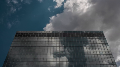 top of skyscraper - looks like UN building with blue sky and clouds - 4K timelapse in Manhattan