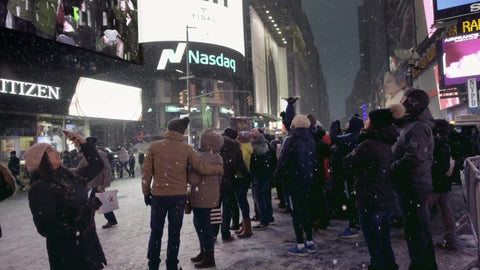 tourists on camera looking at Revlon ad screen - snowing in Times Square at night - winter at night