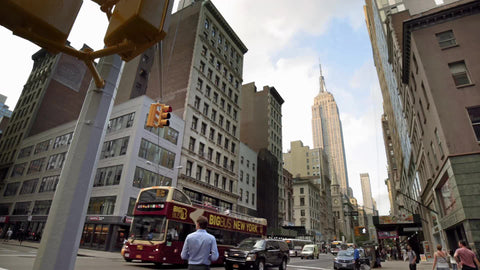 Big Bus Tours driving down 5th Ave with Empire State Building on warm sunny spring day in 4K and 1080 HD in Manhattan NYC