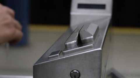 close-up on hand swiping Metro Card at turnstile in subway station in NYC