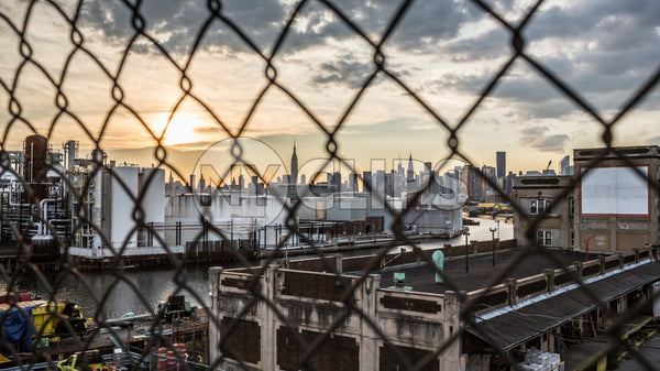 Manhattan skyline view through Brooklyn fence at sunset in NYC