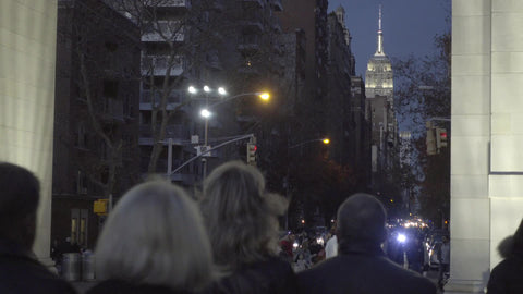 Empire State Building view at night with people walking in Washington Square Park past arch New York City NYC