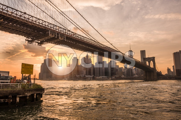 Brooklyn Bridge and Manhattan skyline from across East River at sunset in NYC